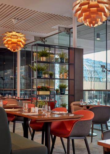 a dining room with tables and chairs and windows at Park Plaza County Hall London in London