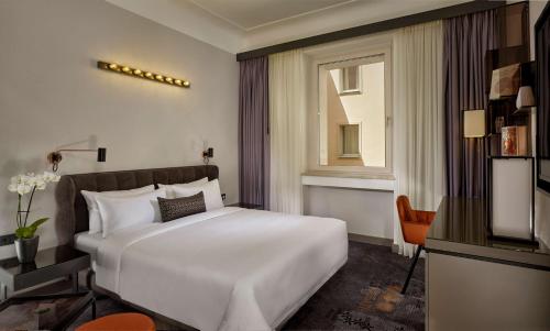 a bedroom with a white bed and a television at Park Plaza Nuremberg in Nürnberg