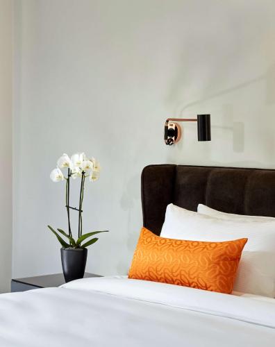 a bed with an orange pillow and a vase with flowers at Park Plaza Nuremberg in Nürnberg