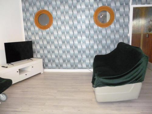 a living room with a television and a chair at Flobart grand appartement à Sangatte au rdc et à 30 metres de la plage in Sangatte
