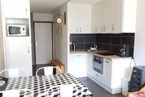 une cuisine avec des armoires blanches et une table avec des chaises dans l'établissement Paradiski calme et ensoleillé plan peisey, à Peisey-Nancroix