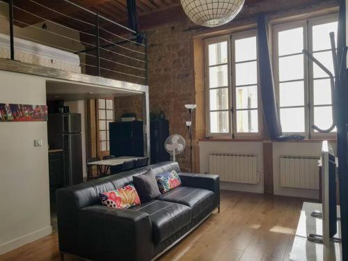 - un canapé en cuir noir dans le salon avec fenêtres dans l'établissement bnbgônes - Le Désiré - HYPER CENTRE VILLE - METRO Hôtel de Ville à 1 mn, à Lyon