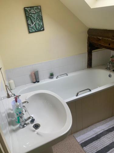 La salle de bains est pourvue d'un lavabo blanc et d'une baignoire. dans l'établissement Becs, à Leominster