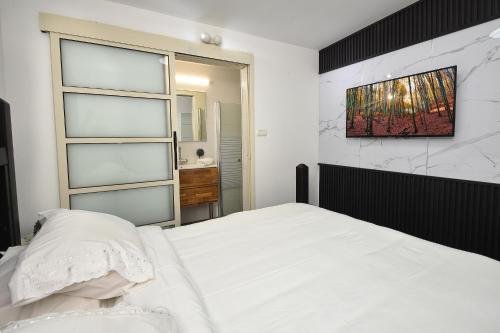 a bedroom with a white bed and a painting on the wall at וילה Vision - וילה מדהימה בקצה היישוב עם בריכה ונוף עוצר נשימה in H̱azon