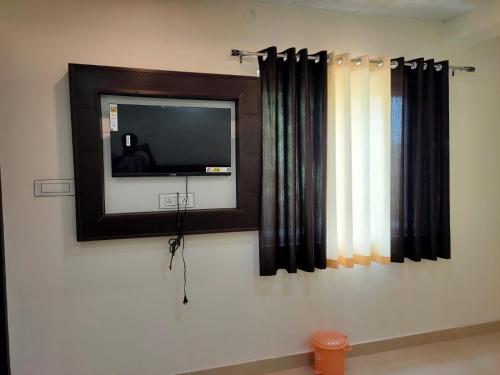 TV de pantalla plana en una pared con cortinas en Hotel Goyal Palace, en Agra