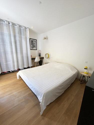Habitación blanca con cama blanca grande y suelo de madera. en Villa contemporaine - Prima Volta, en Niza