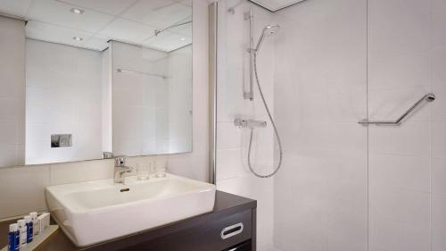 a white bathroom with a sink and a shower at Park Plaza Utrecht in Utrecht