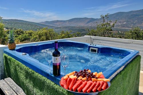 Un jacuzzi con una botella de vino y un plato de fruta. en וילה Vision - וילה מדהימה בקצה היישוב עם בריכה ונוף עוצר נשימה, en H̱azon
