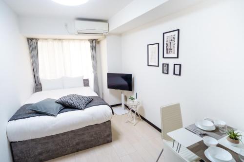 a bedroom with a bed and a table and a television at Green Sea Oshiage 5F in Tokyo