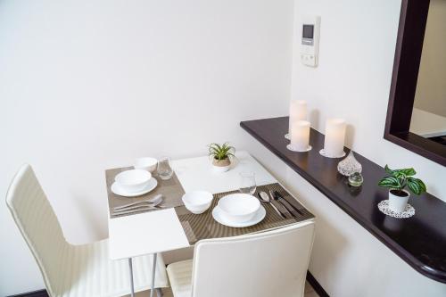 a dining room table with white dishes and candles at Green Sea Oshiage 5F in Tokyo