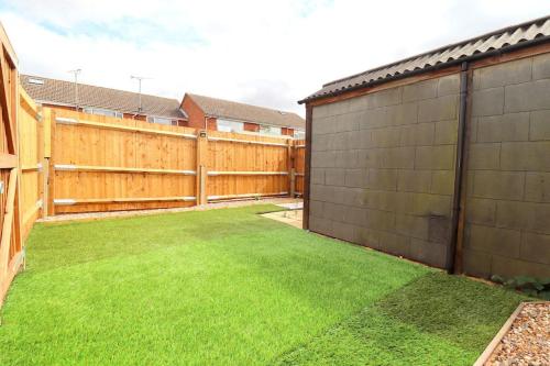 a backyard with a fence and green grass at Luxury Apartment 5 mins to Luton Airport Sleeps 4 in Luton