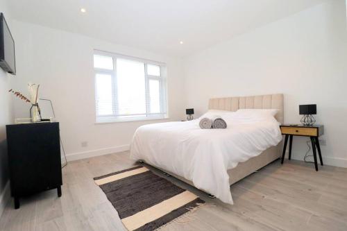 a white bedroom with a large bed and a window at Luxury Apartment 5 mins to Luton Airport Sleeps 4 in Luton