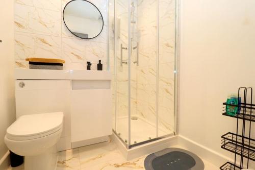 La salle de bains blanche est pourvue d'une douche et de toilettes. dans l'établissement Luxury Apartment 5 mins to Luton Airport Sleeps 4, à Luton
