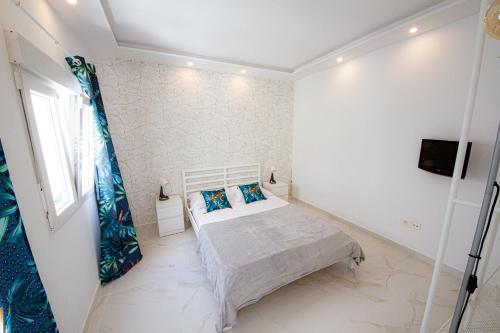 1 dormitorio blanco con 1 cama y TV en Green Point 3 bed holiday House, en Arona