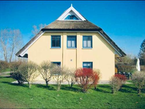 uma grande casa branca com um telhado de gambrel em Komfortables Reetdachferienhaus Hasel 1 em Puddemin
