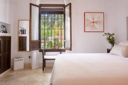 Un dormitorio con una cama y una ventana y una silla. en Andalusian Villa w/ Pool, Garden & Barbecue, en Écija