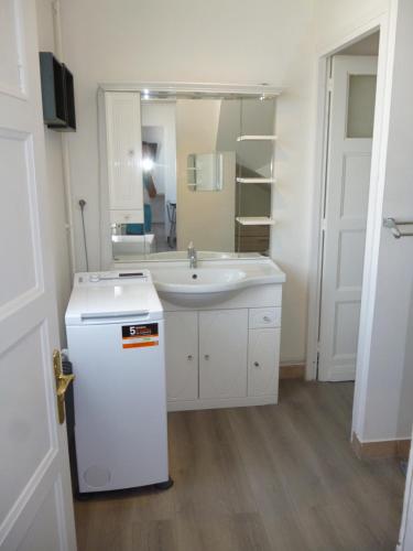 a white bathroom with a sink and a mirror at Cambuse Appartement à Sangatte au premier étage à 50 metres de la plage in Sangatte