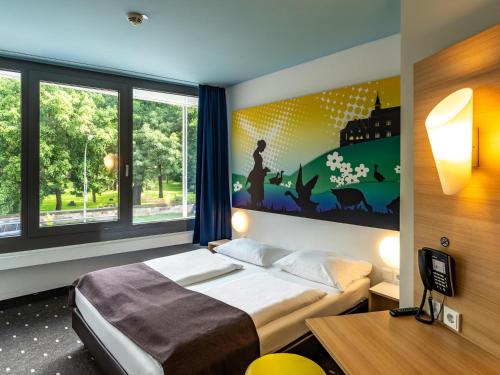ein Schlafzimmer mit einem Bett und einem großen Fenster in der Unterkunft B&B Hotel Göttingen-City in Göttingen