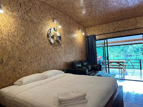 a bedroom with a bed and a chair and a window at ธารามนตรา รีสอร์ท (Taramontra resort) in Tha Kradan