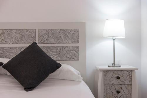 a bedroom with a bed with a black pillow and a lamp at Paloma Beach Apartments in Los Cristianos
