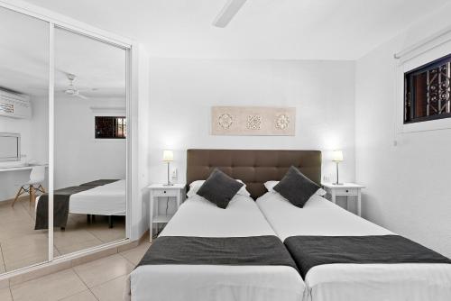 a bedroom with two beds and a mirror at Paloma Beach Apartments in Los Cristianos