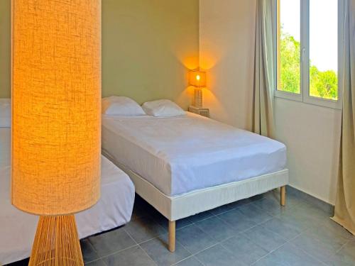 a bedroom with a bed and a lamp next to a window at Résidence Maora Village in Bonifacio