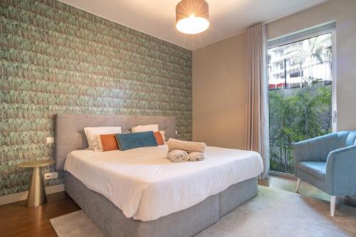 um quarto com uma cama e uma cadeira azul em Madeira Residence Apartment AK5 no Funchal