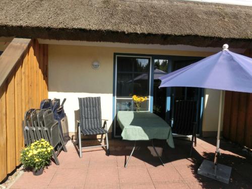 a patio with a table and chairs and an umbrella at Reetdachhaus Malve 3 im Feriendorf Puddeminer Wiek in Puddemin