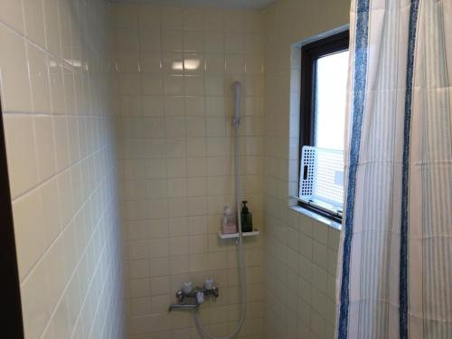 a bathroom with a shower with a shower curtain at Guesthome Machiya Koza in Okinawa City