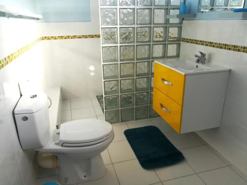 a bathroom with a white toilet and a yellow cabinet at Calme Villa in Sainte-Rose