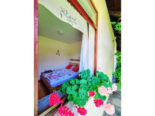 a room with a bed and flowers in a window at Apartma Stanka in Bistrica ob Sotli