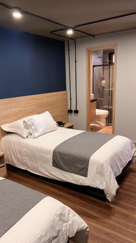 a bedroom with a large bed and a bathroom at Hotel D' Leon in Bucaramanga