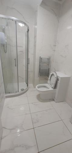 La salle de bains blanche est pourvue d'une douche et de toilettes. dans l'établissement Leicester City Apartments, à Leicester