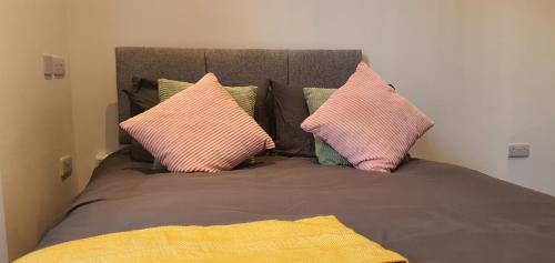 una cama con almohadas rosas en una habitación en Leicester City Apartments en Leicester