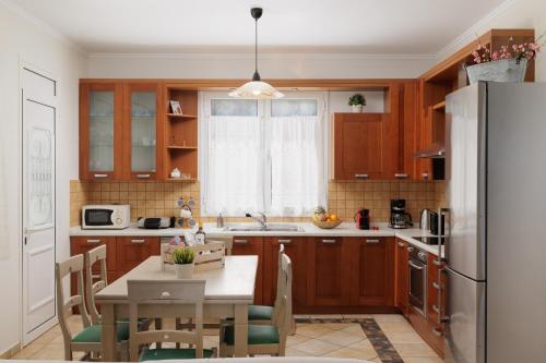 uma cozinha com armários de madeira, uma mesa e um frigorífico em Beachfront Villa Dionysos - With private beach em Sidari