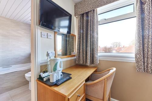 a room with a desk with a computer and a tv at Properties Unique Dene Rooms - Family Room in Newcastle upon Tyne