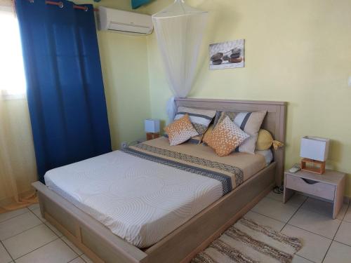 1 dormitorio con 1 cama con cortina azul en Calme Villa en Sainte-Rose