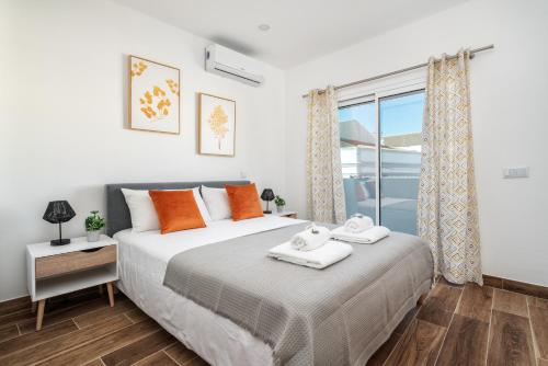 a bedroom with a bed with orange pillows and a window at Privilege Casa dos Capuchinhos, in the heart of Faro in Faro