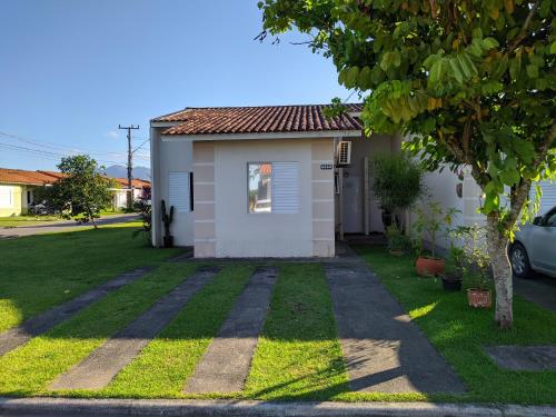 una pequeña casa blanca con un patio de césped en Casa na Grande Florianopolis en Palhoça