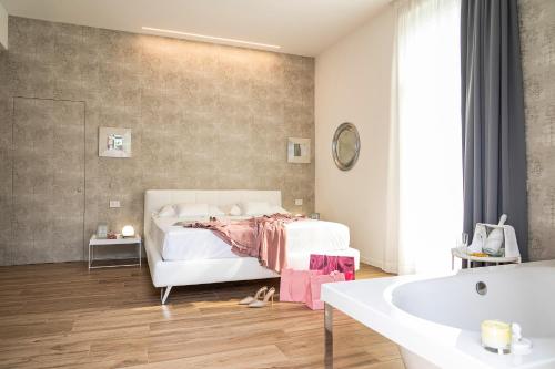 - une chambre avec un lit blanc et une baignoire dans l'établissement Villa Tosati, à Monza