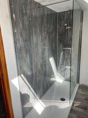 a shower with a glass door in a bathroom at 3 Bedroom Townhouse on NC500, Wick, Highland in Wick