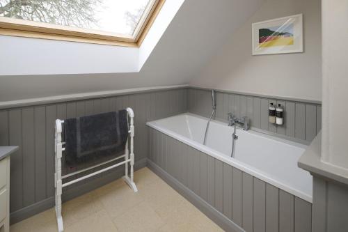 a bathroom with a bath tub and a window at Dunaincroy Farmhouse in Inverness