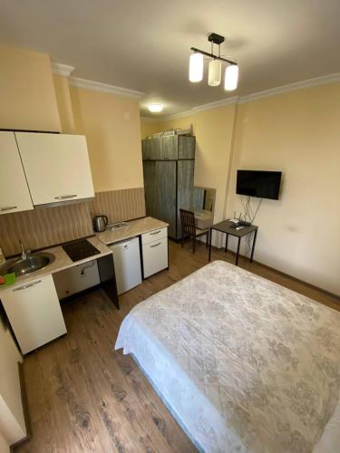 a bedroom with a bed and a kitchen and a table at Квартира у моря Колхида in Makhinjauri