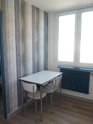 une table et des chaises dans une pièce avec deux fenêtres dans l'établissement Gentlemen appartement au premier étage à 50 metres de la mer, à Sangatte
