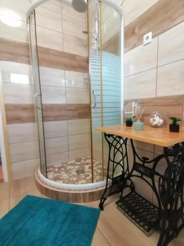 a shower in a room with a wooden table at Őrségi Lápréti Vendégház in Szőce
