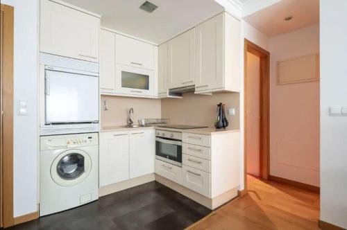 a kitchen with white cabinets and a washer and dryer at Apartamento Centro de Baiona con Parking in Baiona