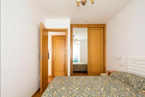 a bedroom with a bed and a door leading into a room at Apartamento Centro de Baiona con Parking in Baiona