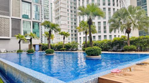 ein großer Swimmingpool mit Palmen und Gebäuden in der Unterkunft Soho Suites KLCC By Grand Suites KL in Kuala Lumpur