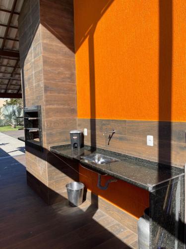 a bathroom with a sink and an orange wall at Faith Home 2 in Arraial do Cabo