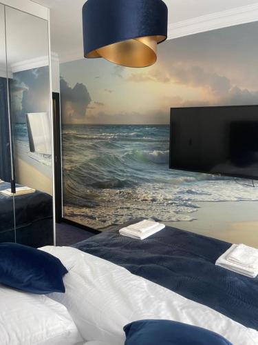 a bedroom with a painting of the ocean on the wall at Baltic Apartment in Gdańsk